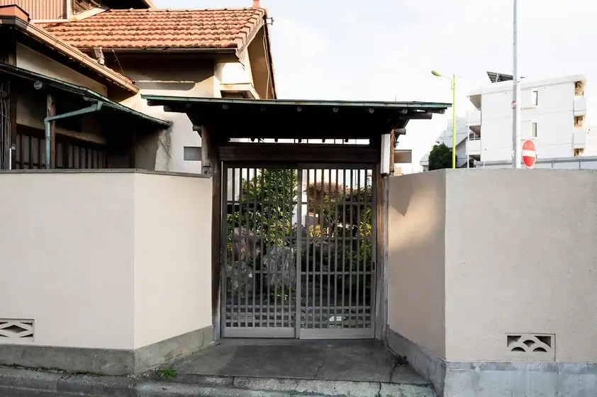 Slatted metal courtyard gate between stucco walls