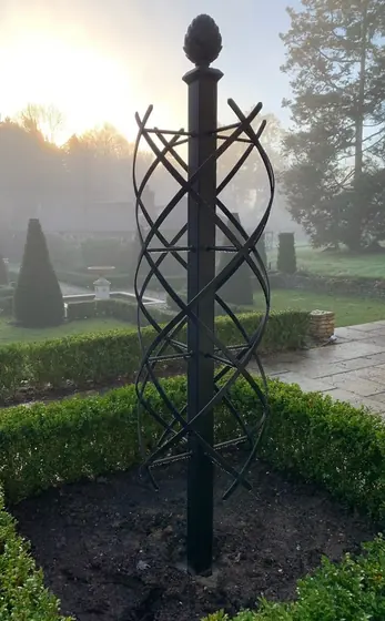 Twisted iron obelisk in a misty formal garden