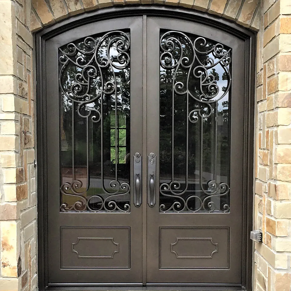 Wrought-iron double entry doors with hand-scrolled grilles, set in a stone arch