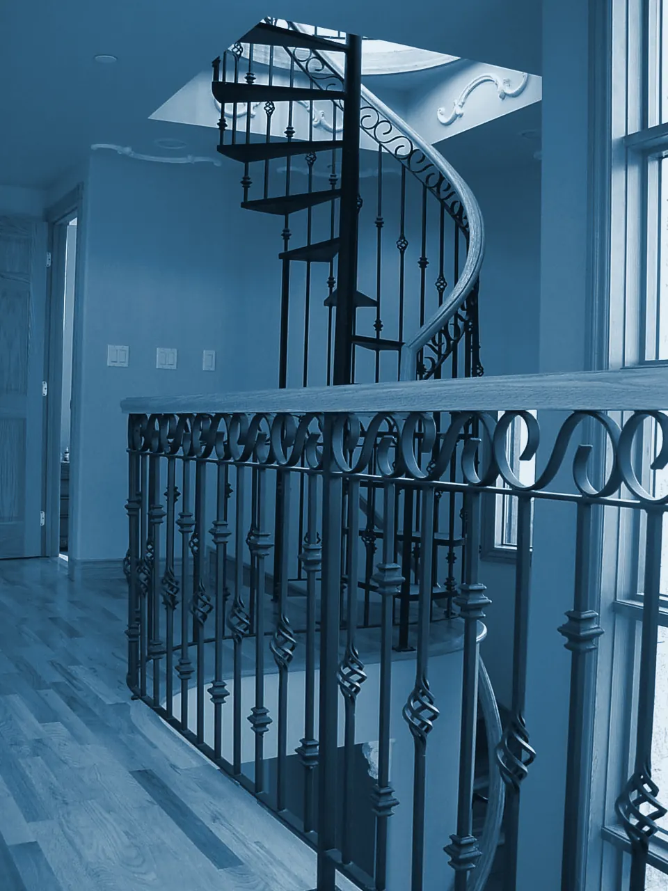 Scrolled iron balusters and a spiral staircase, toned steel blue